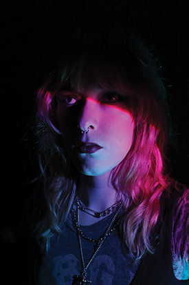 Photograph of a girl's face illuminated by pink and blue lights.